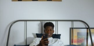 Cyfrowe nawyki, które psują sen i zdrowie psychiczne, oraz jak je zmienić Młody mężczyzna w łóżku przegląda smartfon przed snem