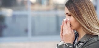 Jak zmiany klimatu wpływają na alergie sezonowe: aktualne prognozy lekarzy i nowe metody leczenia Kobieta kicha na zewnątrz, trzyma chusteczkę i maseczkę